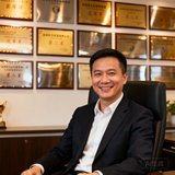 深圳龙岗赛事公司李总在办公室内自信微笑，背后是公司承办的多场赛事奖牌展示墙。